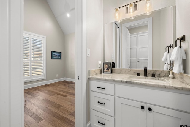 bathroom with vaulted ceiling, hardwood / wood-style floors, and vanity