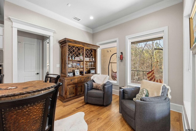 sitting room with bar, ornamental molding, and light hardwood / wood-style floors