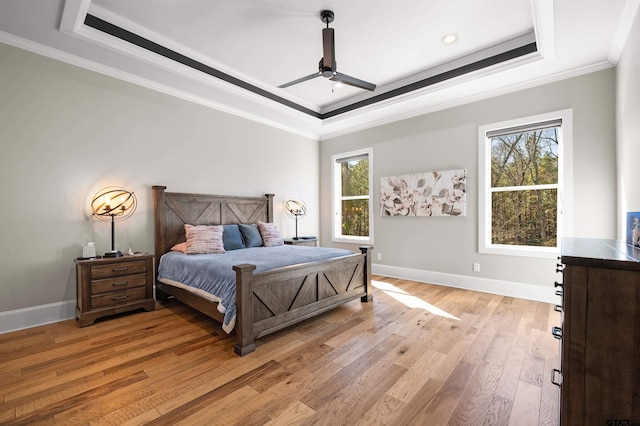 bedroom with a raised ceiling, ornamental molding, and light wood-type flooring