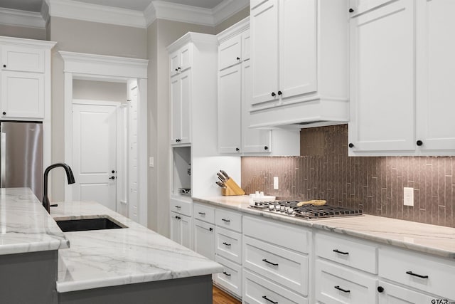 kitchen featuring sink, white cabinetry, crown molding, appliances with stainless steel finishes, and light stone countertops