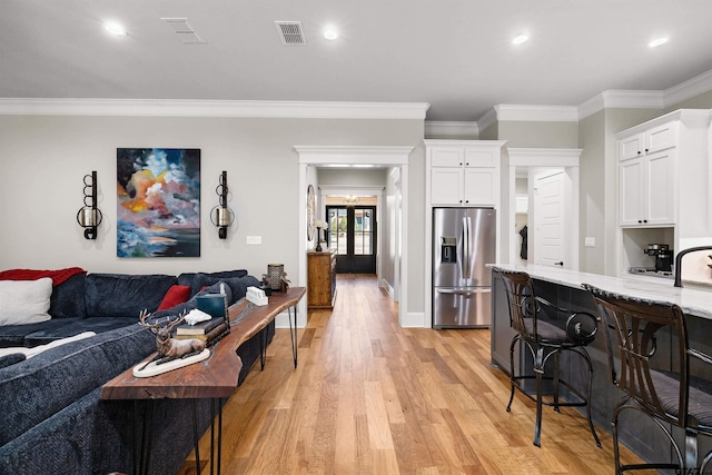 kitchen featuring ornamental molding, stainless steel fridge with ice dispenser, light hardwood / wood-style flooring, and white cabinets