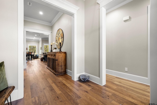 corridor with wood-type flooring and crown molding