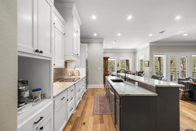 kitchen featuring white cabinetry, an island with sink, sink, and light hardwood / wood-style floors