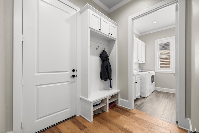 mudroom with ornamental molding, washing machine and dryer, and light wood-type flooring