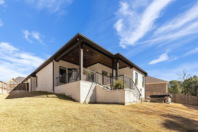 back of property featuring a hot tub and a lawn