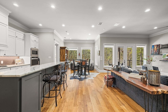 kitchen with appliances with stainless steel finishes, white cabinetry, a kitchen breakfast bar, a large island, and light stone countertops