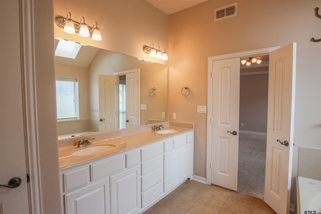 bathroom with a sink, tile patterned flooring, a tub to relax in, and visible vents