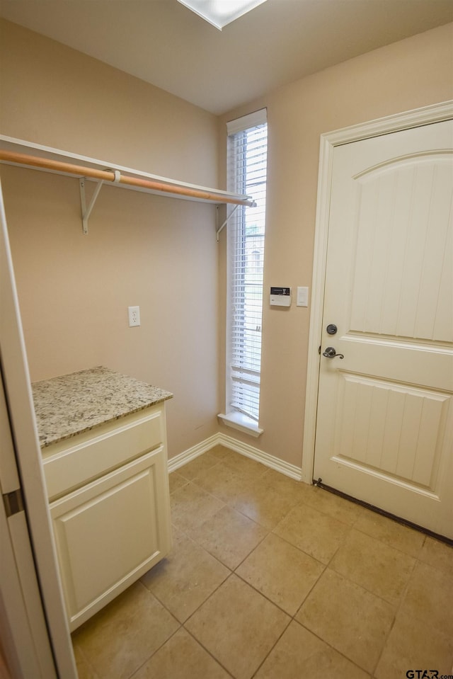 laundry area featuring baseboards, laundry area, and light tile patterned flooring