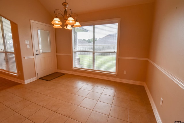 foyer featuring baseboards, a notable chandelier, light tile patterned floors, and vaulted ceiling
