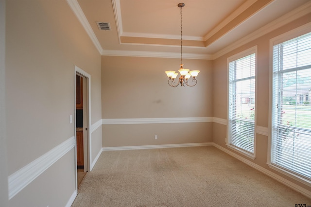 unfurnished room featuring light colored carpet, visible vents, an inviting chandelier, ornamental molding, and a tray ceiling