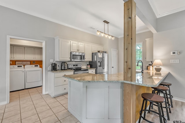 14677 County Road 2337, Tyler, TX 75707 - kitchen with stainless steel appliances, independent washer and dryer, ornamental molding, a peninsula, and a kitchen bar