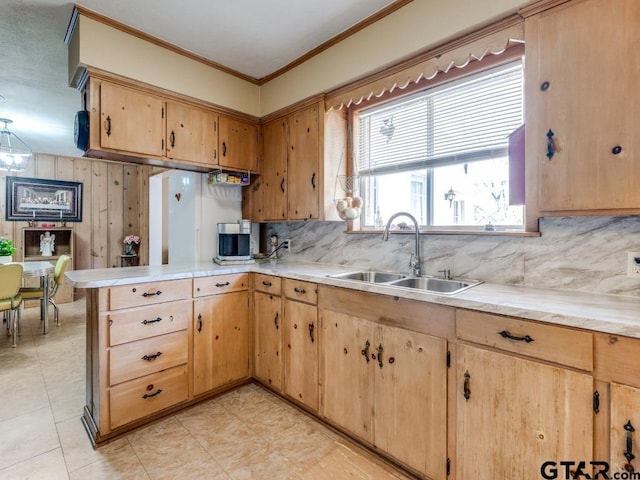 kitchen featuring crown molding, kitchen peninsula, sink, and backsplash