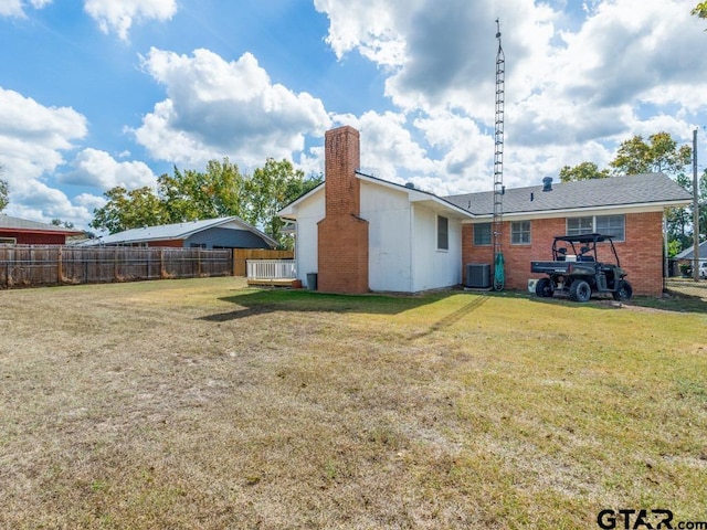 rear view of house with a yard and central AC