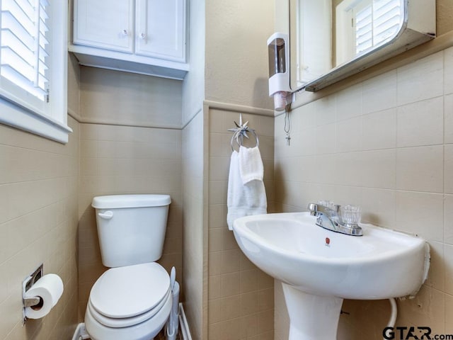 bathroom featuring tile walls, sink, and toilet