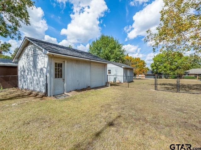 rear view of house featuring a garage, an outdoor structure, and a lawn