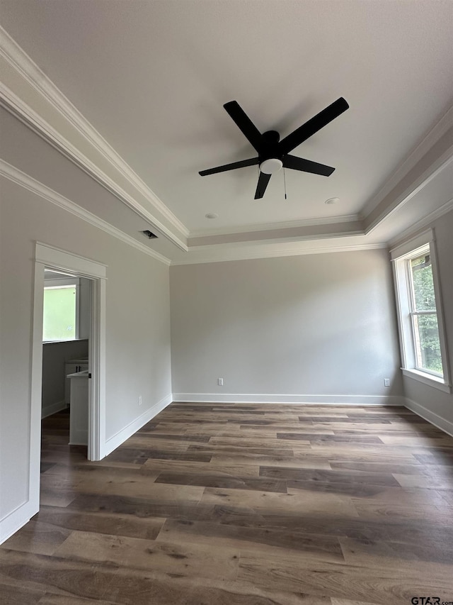 unfurnished room featuring dark wood finished floors, ornamental molding, and a raised ceiling