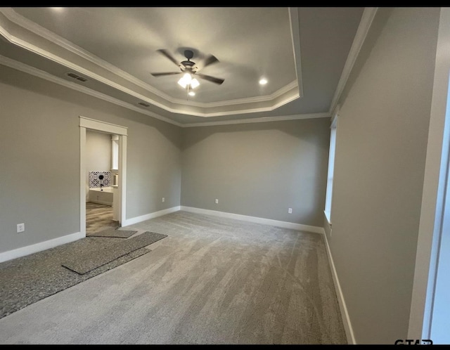 empty room featuring carpet flooring, visible vents, baseboards, ornamental molding, and a tray ceiling