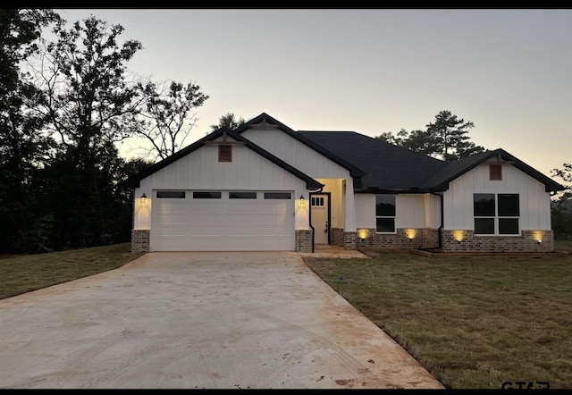 view of front of house featuring concrete driveway, brick siding, a lawn, and an attached garage