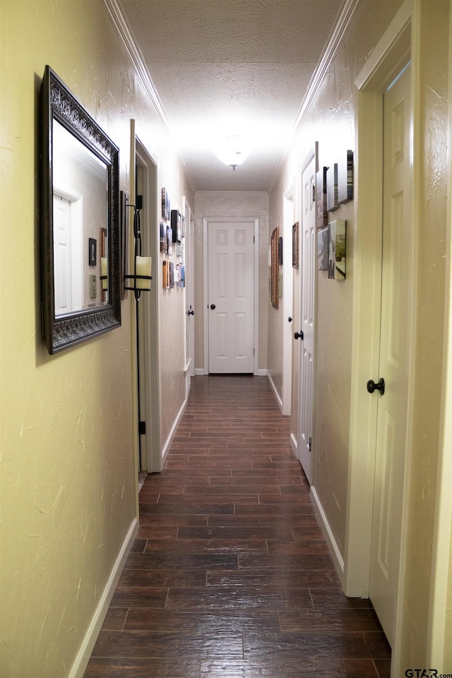 corridor featuring dark wood-type flooring, a textured ceiling, and crown molding