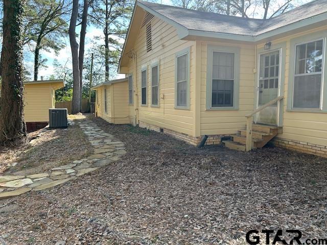 view of home's exterior with entry steps, fence, central AC, and crawl space