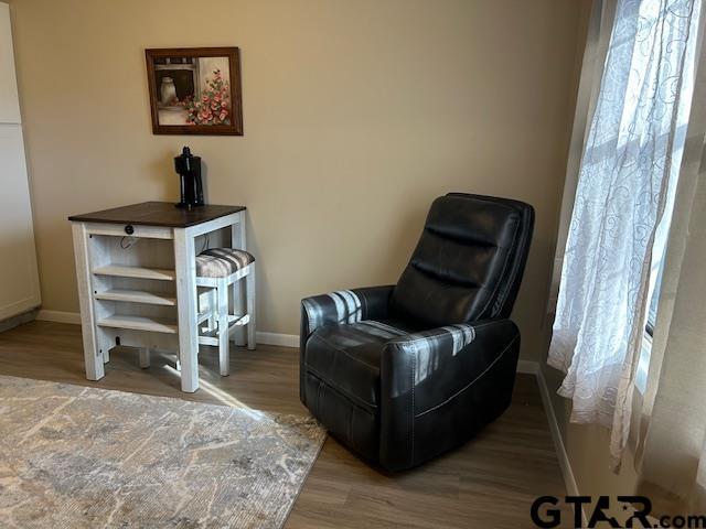 living area with baseboards and wood finished floors