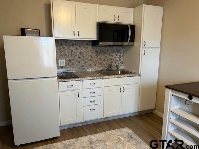 kitchen featuring decorative backsplash, dark wood-style flooring, white cabinets, freestanding refrigerator, and black electric stovetop