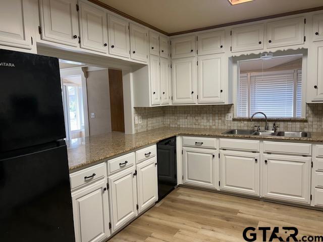kitchen featuring a sink, decorative backsplash, black appliances, and white cabinets