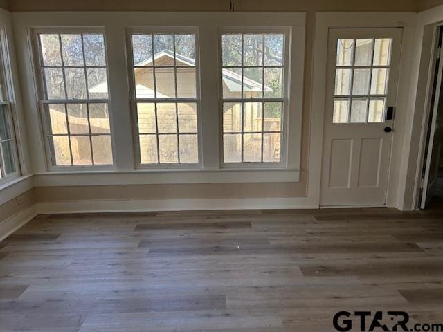 doorway to outside featuring baseboards and wood finished floors