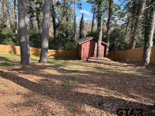 view of yard featuring an outbuilding, a fenced backyard, and a storage unit