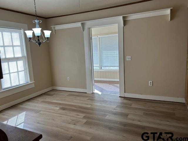 unfurnished dining area with a healthy amount of sunlight, baseboards, and a notable chandelier