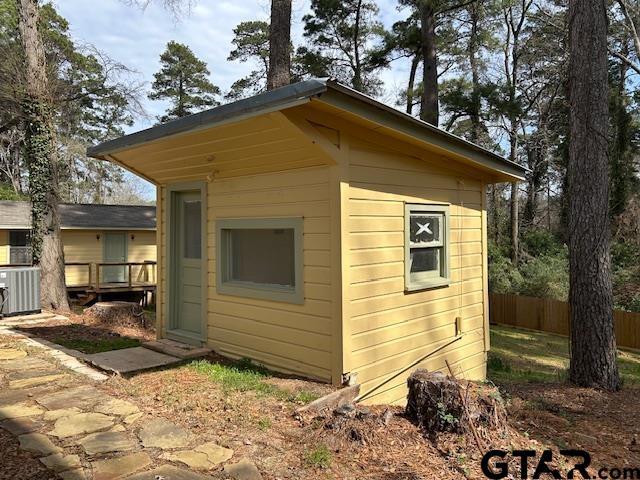 view of outbuilding with fence, an outdoor structure, and cooling unit
