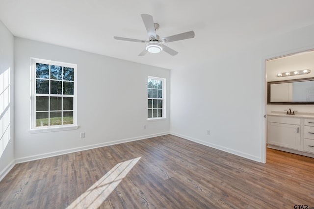 unfurnished bedroom featuring multiple windows, wood-type flooring, connected bathroom, and ceiling fan