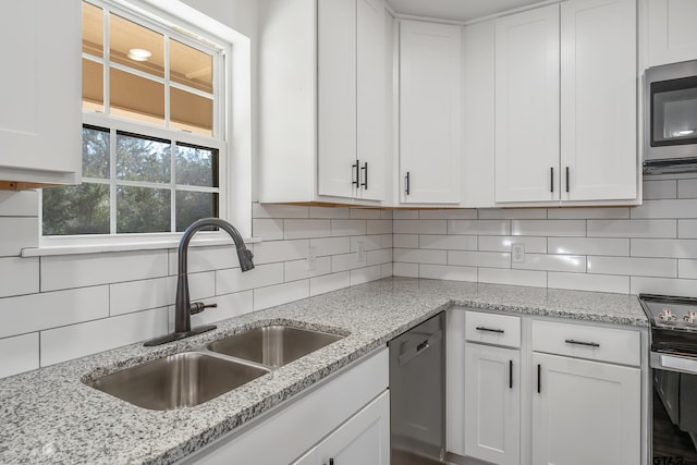 kitchen featuring sink, white cabinetry, appliances with stainless steel finishes, light stone countertops, and backsplash