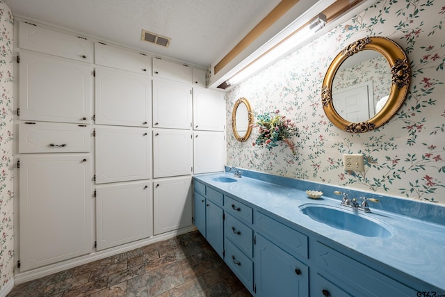 507 E Longview St, Arp, TX 75750 - full bathroom with wallpapered walls, double vanity, stone finish flooring, and a textured ceiling