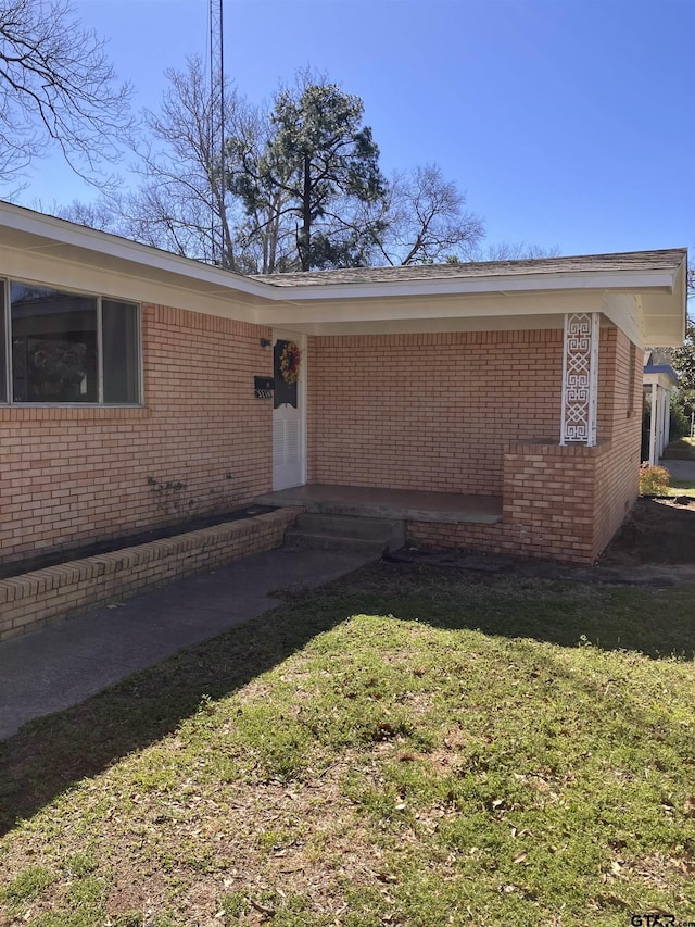 property entrance with brick siding and a lawn