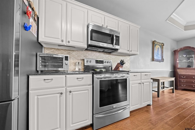 1521 Rice Rd # A105, Tyler, TX 75703 - kitchen with appliances with stainless steel finishes, light wood-style floors, decorative backsplash, white cabinets, and ornamental molding