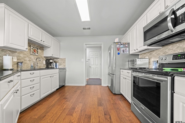 1521 Rice Rd # A105, Tyler, TX 75703 - kitchen with stainless steel appliances, white cabinetry, dark countertops, and decorative backsplash