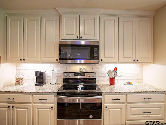 kitchen featuring stainless steel appliances, light stone counters, and tasteful backsplash