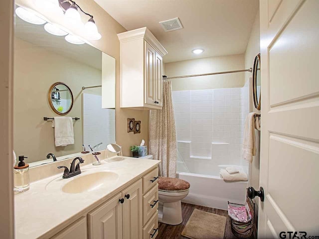 full bath with visible vents, vanity, wood finished floors, toilet, and shower / bath combo