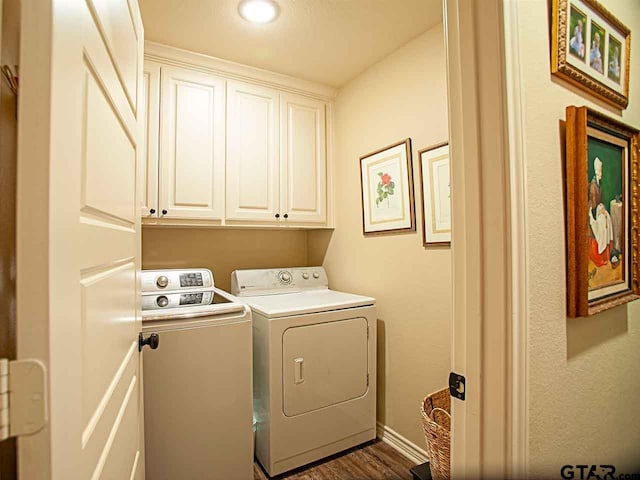 laundry room featuring washing machine and clothes dryer, baseboards, dark wood finished floors, and cabinet space