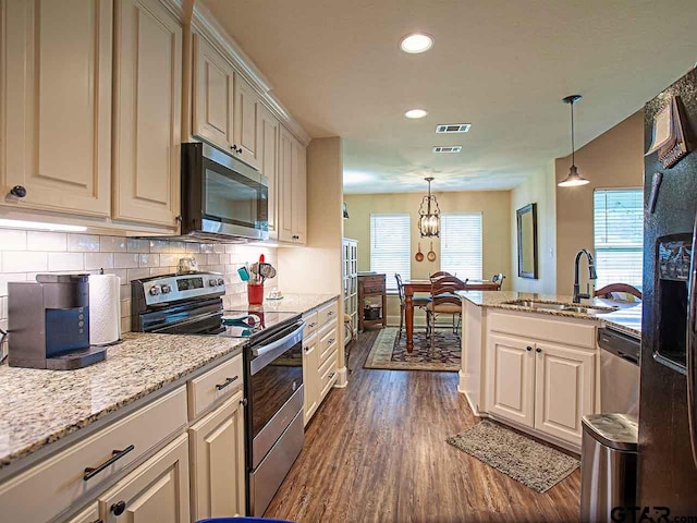 kitchen with a sink, stainless steel appliances, decorative backsplash, visible vents, and dark wood-style floors