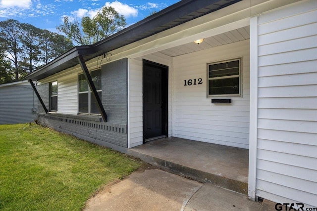 1612 Woodland Hills Dr, Tyler, TX 75701 - view of exterior entry with a porch, brick siding, and a lawn