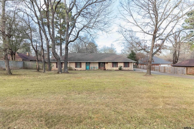 exterior space featuring brick siding, fence, and a front lawn