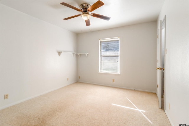 carpeted spare room with ceiling fan and baseboards