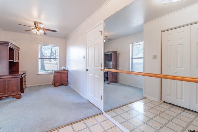 interior space featuring ornamental molding, light carpet, ceiling fan, and baseboards