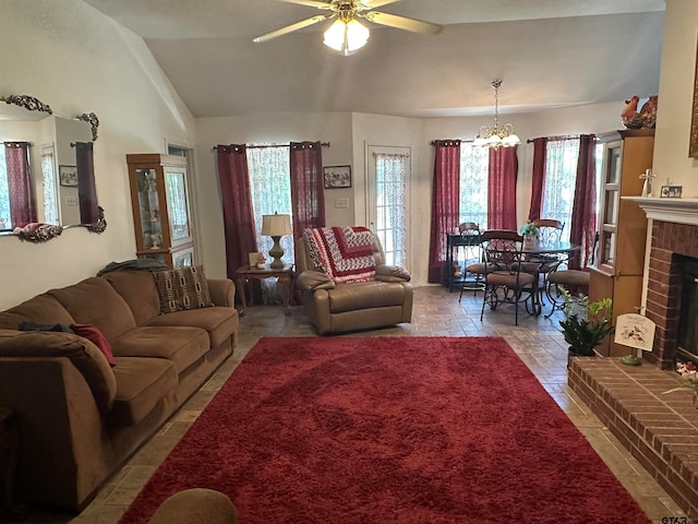 living room with a brick fireplace, ceiling fan with notable chandelier, and vaulted ceiling