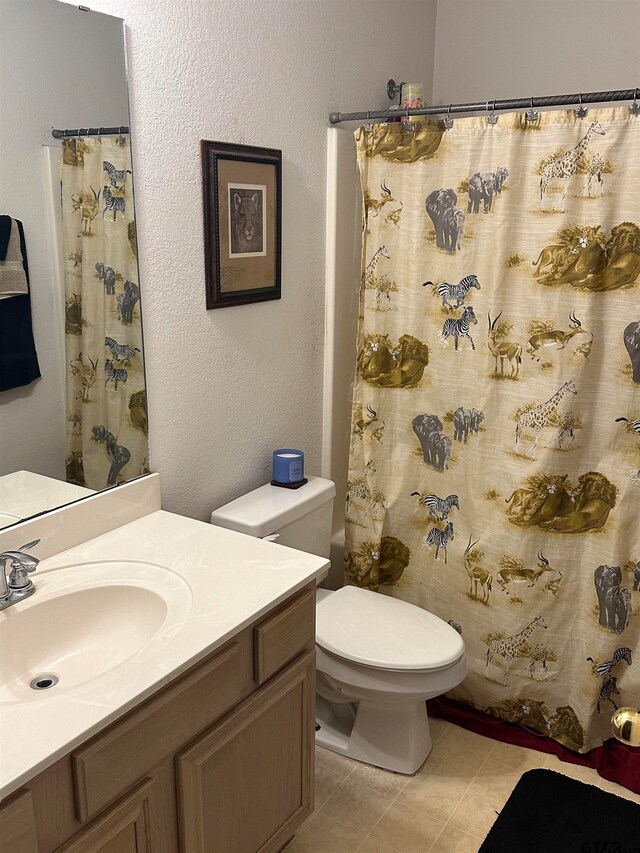 bathroom featuring toilet, walk in shower, vanity, and tile patterned floors