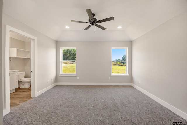 unfurnished bedroom with connected bathroom, multiple windows, vaulted ceiling, and ceiling fan