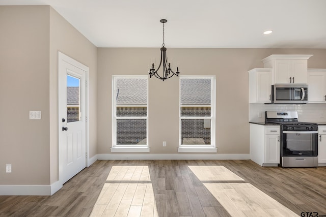 kitchen with an inviting chandelier, white cabinets, light hardwood / wood-style flooring, tasteful backsplash, and appliances with stainless steel finishes