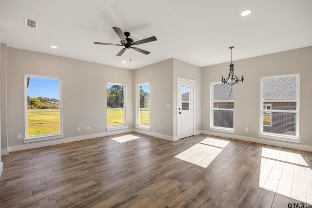 unfurnished room with ceiling fan with notable chandelier and dark hardwood / wood-style floors